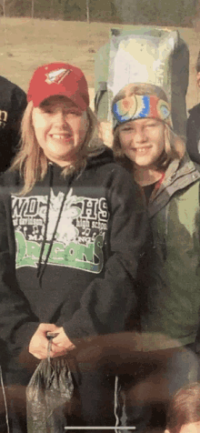 two girls are posing for a picture and one has a hoodie that says ' woods high school ' on it