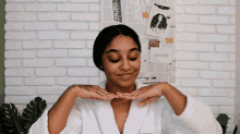 a woman in a bathrobe is smiling in front of a white brick wall with a poster that says power