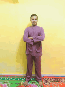 a man in a purple shirt and pants is standing with his arms crossed