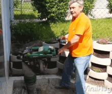 a man in an orange shirt is standing in front of a machine that says ' jl500-2 ' on it