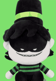 a black and white stuffed animal with a green ribbon around its hat