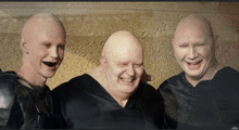 three bald men are posing for a photo and smiling