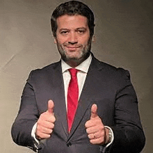 a man in a suit and tie is giving a thumbs up sign .