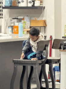 a little boy sits on a wooden chair in front of a counter with a box that says ' honey ' on it