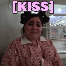 a woman wearing a pink sweater with the word kiss written on it