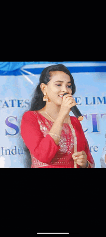 a woman in a red dress is singing into a microphone at a concert .