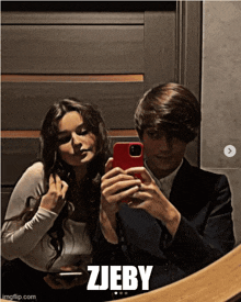 a man and a woman are taking a selfie in front of a mirror with the words zjeby below them