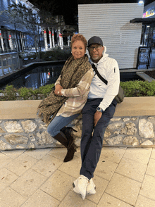 a man and a woman are sitting on a stone wall in front of a building that has a sign that says terminal on it