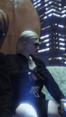 a woman wearing sunglasses and a black jacket is sitting in front of a city at night