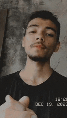 a young man with a beard and mustache is making a heart shape with his hands .