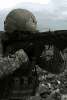 a man in a military uniform is holding a rifle and wearing a helmet with the letter t on it