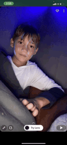 a phone screen shows a boy with blue paint on his face and the time 2:58