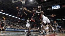 a basketball player wearing a heat jersey tries to get the ball