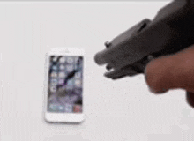 a person is holding a gun to a cell phone .