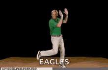 a man in a green shirt and white pants is dancing in front of a black background with the word eagles written on it .