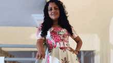 a woman in a floral dress is standing on a staircase .