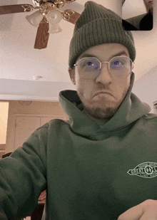 a man wearing glasses and a green hoodie that says " great outdoors "