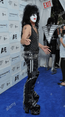 a man in a kiss costume stands on a blue carpet