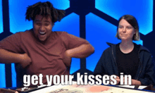 a man and woman are sitting at a table with the words get your kisses in