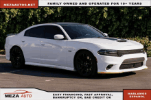 a white dodge charger sits in a parking lot