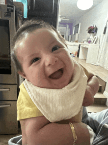 a baby wearing a bib is smiling in front of a samsung fridge