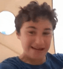 a young boy with curly hair is making a funny face while taking a selfie .