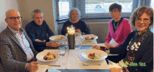 a group of people are sitting at a table with plates of food and glasses of water and the number 21 on the bottom right corner