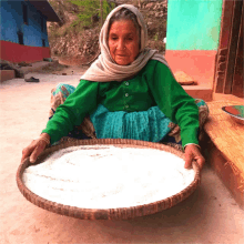 an elderly woman in a green sweater is holding a tray of food