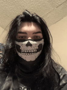 a person with long hair wearing a black and white skull face mask