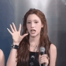a woman is singing into a microphone and making a funny face .