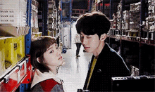 a man and a woman are standing in a warehouse looking at each other .