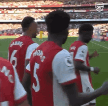 a group of soccer players are standing on a field and one of them has the number 5 on his shirt .