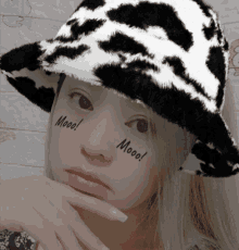 a woman wearing a black and white cow print hat has mooo written on her face