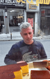 a man standing in front of a store that says ' rat kizilates '