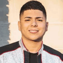 a young man is smiling for the camera while wearing a jacket and a black shirt .