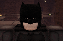 a close up of batman 's face with a brick wall in the background