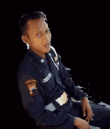 a man in a black uniform is sitting in front of a sign that says " masuk pak eko "