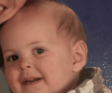 a close up of a baby 's face with a woman holding him