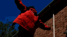 a person in a red and black jacket is hanging from a gutter