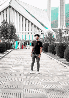 a man standing in front of a building with a black shirt that says ' samsung ' on the front