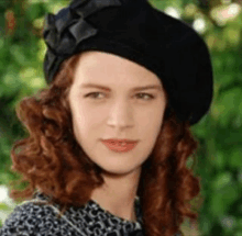 a woman wearing a black beret and a leopard print shirt is looking at the camera .