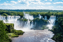 a large waterfall is surrounded by trees and a river