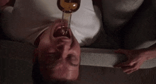 a man is laying on his back with a bottle of alcohol in his mouth