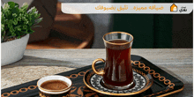 a cup of coffee sits on a tray with arabic writing on it