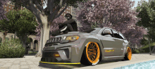 a man sits on the hood of a jeep with orange tires