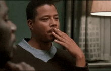 a man is covering his mouth with his hand in a room .
