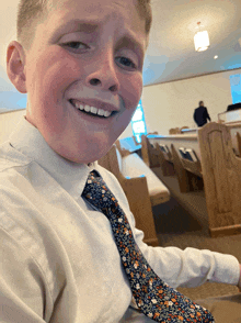 a young boy wearing a tie and a white shirt smiles in a church