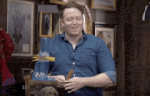 a man in a denim shirt is holding a pencil in front of a stack of sticks