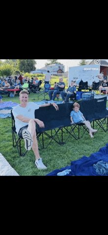 a man and two children are sitting in folding chairs in a park .