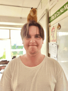 a man with a stuffed animal on his head in front of a sign that says uk